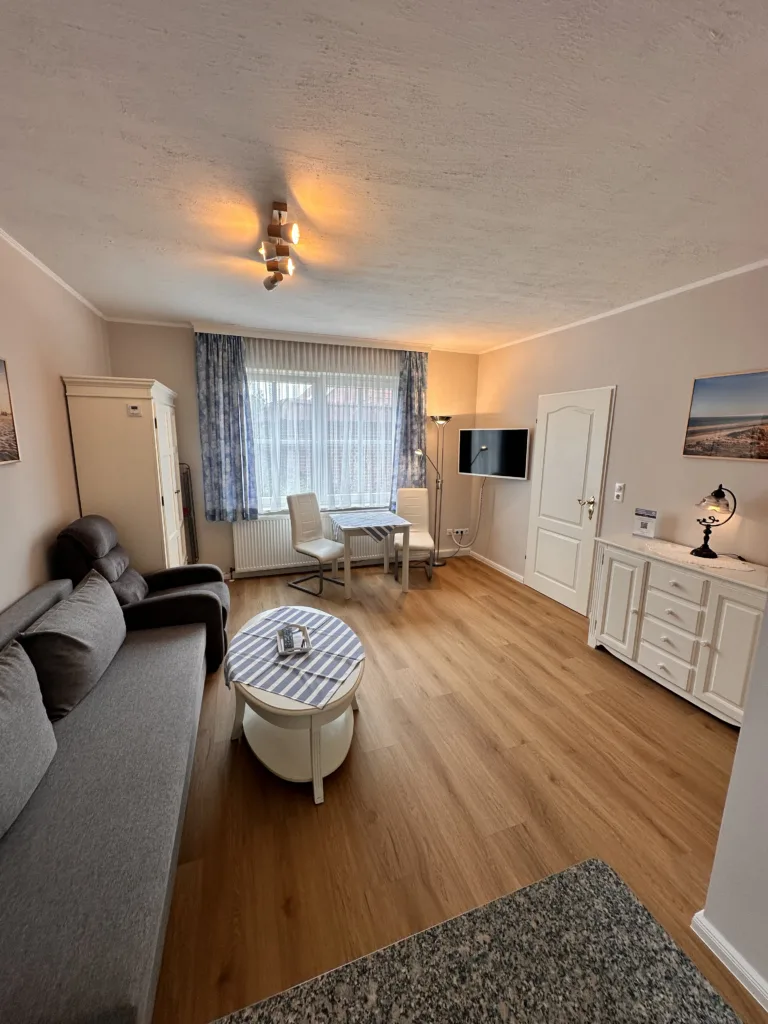 Cozy living room in Haus Hubertus on Borkum featuring a comfortable sofa, dining area, flat-screen TV, and bright, inviting decor for your vacation.